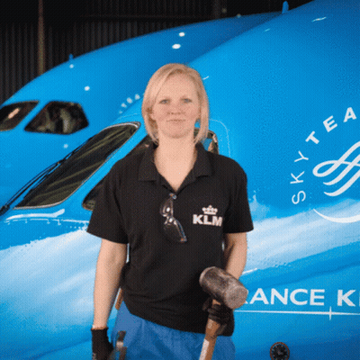 A Woman Stands In Front Of A Blue Sky Tea Plane GIF