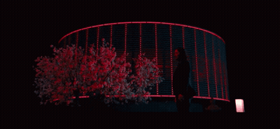 A Woman Stands In Front Of A Building That Is Lit Up With Red Lights GIF
