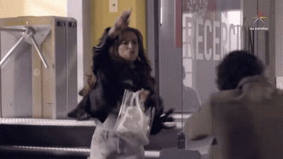 A Woman Stands In Front Of A Glass Door That Says Recepcion GIF
