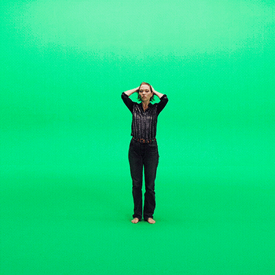 A Woman Stands In Front Of A Green Screen GIF