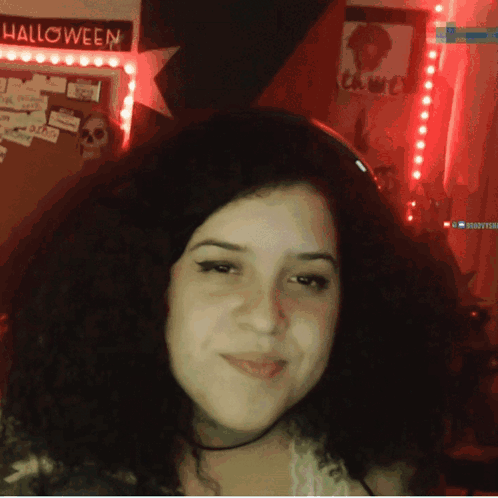 A Woman Stands In Front Of A Halloween Sign GIF