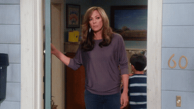 A Woman Stands In Front Of A House With The Number 60 On The Side GIF