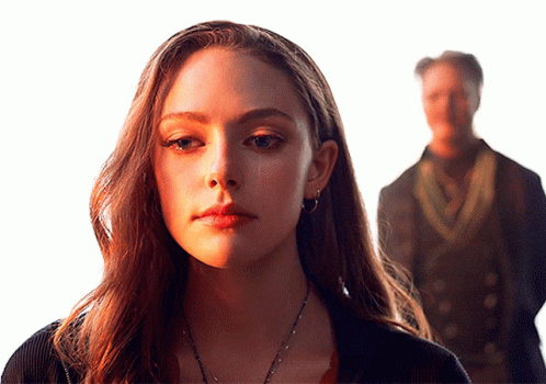 A Woman Stands In Front Of A Man In A Dark Suit GIF