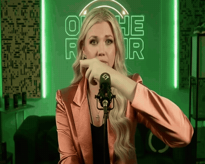 A Woman Stands In Front Of A Microphone In Front Of A Neon Sign That Says Othe R GIF