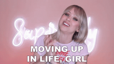 A Woman Stands In Front Of A Neon Sign That Says Moving Up In Life Girl GIF