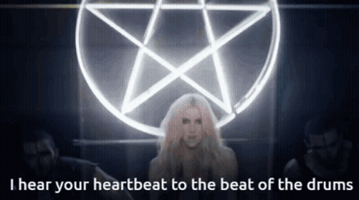 A Woman Stands In Front Of A Pentagram With The Words I Hear Your Heartbeat To The Beat Of The Drums GIF