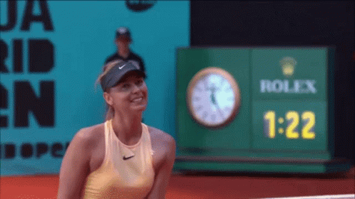 A Woman Stands In Front Of A Rolex Clock GIF