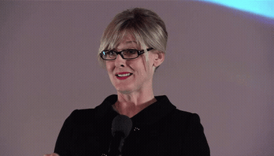 A Woman Stands In Front Of A Screen That Says Dust On It GIF