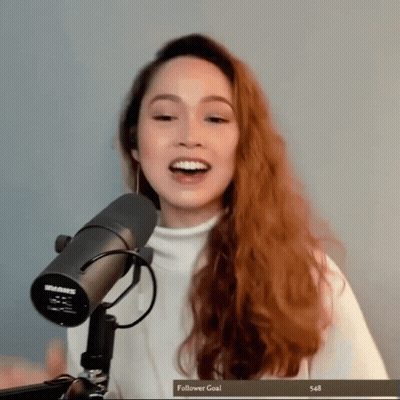 A Woman Stands In Front Of A Shure Microphone With A Follower Goal Of 548 GIF