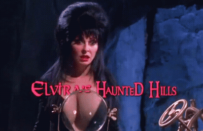A Woman Stands In Front Of A Sign That Says Elvira 'S Haunted Hills On It GIF