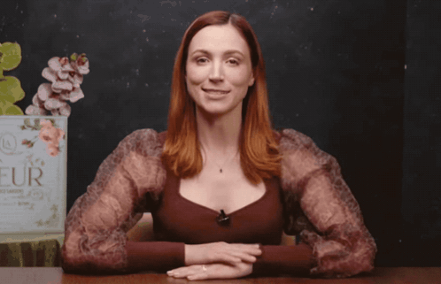A Woman Stands In Front Of A Sign That Says Fleur On It GIF
