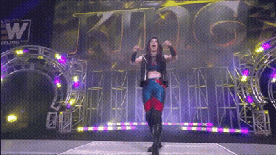 A Woman Stands In Front Of A Sign That Says King On It GIF