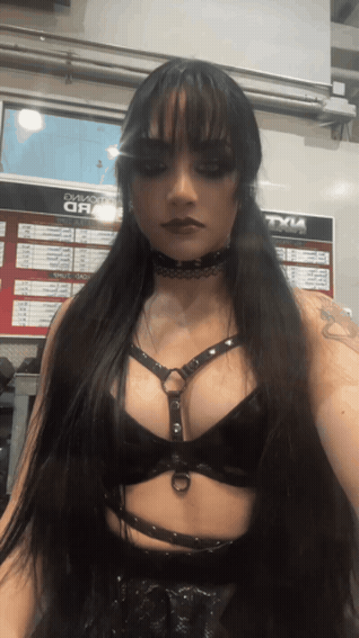 A Woman Stands In Front Of A Sign That Says Tyle On It GIF