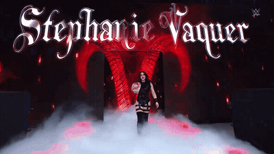 A Woman Stands In Front Of A Stage With The Name Stephanie Vaquer Written On It GIF