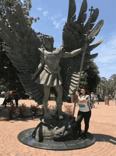 A Woman Stands In Front Of A Statue That Says Strength From The Lord On It GIF