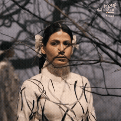 A Woman Stands In Front Of A Tree With The Words Lakme Fashion Week Next On The Bottom Right GIF