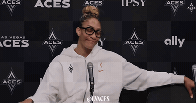 A Woman Stands In Front Of A Wall That Says Aces And Ally GIF