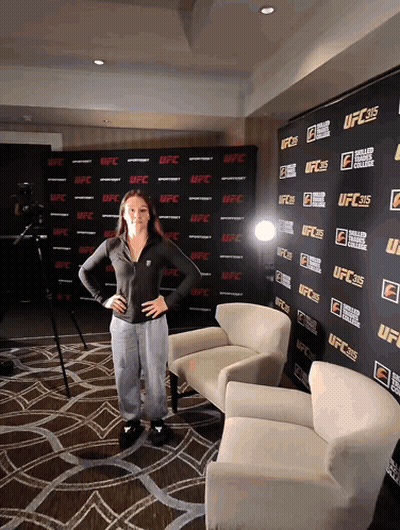 A Woman Stands In Front Of A Wall That Says Ufc On It GIF