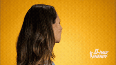 A Woman Stands In Front Of A Yellow Background With The Words 5 Hour Energy On It GIF
