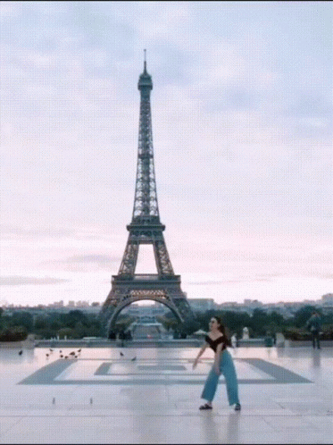 A Woman Stands In Front Of The Eiffel Tower In Paris GIF