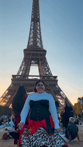 A Woman Stands In Front Of The Eiffel Tower Wearing A Leopard Print Skirt GIF