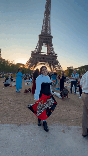 A Woman Stands In Front Of The Eiffel Tower Wearing A Leopard Print Skirt GIF