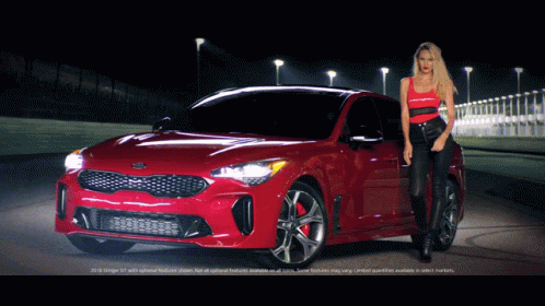 A Woman Stands Next To A Red Kia Stinger GIF