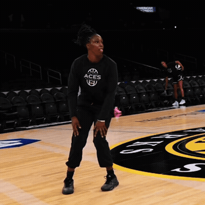 A Woman Stands On A Basketball Court Wearing A Black Aces Shirt GIF