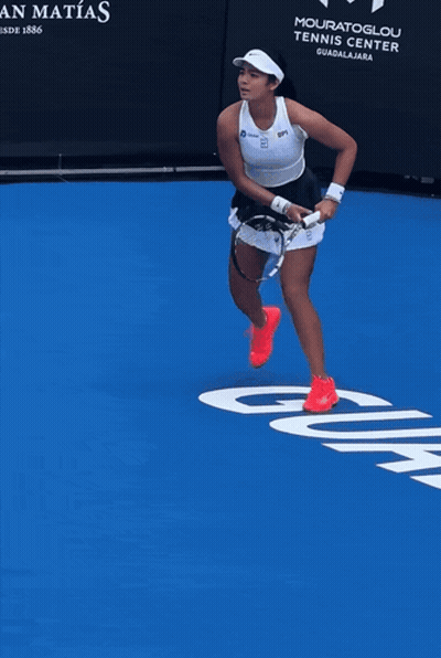 A Woman Stands On A Blue Tennis Court In Front Of A Sign That Says Casa San Matos GIF