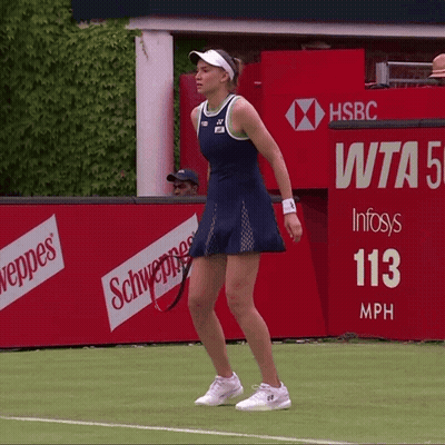 a woman stands on a tennis court in front of a hsbc banner