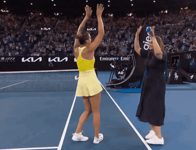 A Woman Stands On A Tennis Court With A Sign That Says Emirates Emir On It GIF