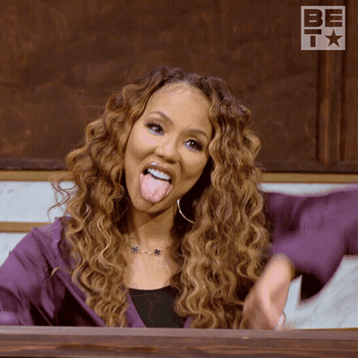 A Woman Sticking Her Tongue Out In Front Of A Sign That Says Be T GIF