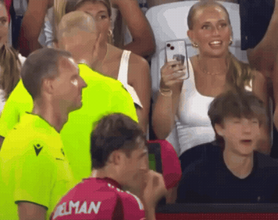 A Woman Takes A Picture Of A Man Wearing A Jersey That Says ' Elman ' On It GIF