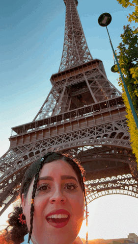 A Woman Taking A Picture In Front Of The Eiffel Tower GIF