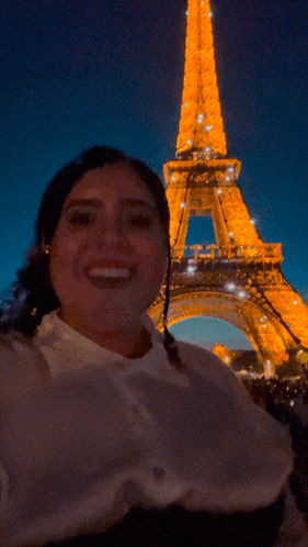 A Woman Taking A Picture In Front Of The Eiffel Tower GIF