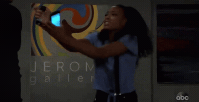 A Woman Taking A Picture Of Herself In Front Of A Sign That Says Jerom Galler GIF
