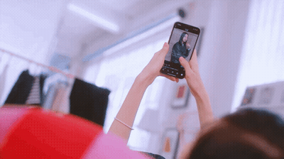 A Woman Taking A Picture Of Herself With A Cell Phone GIF