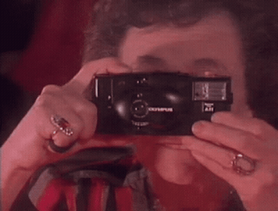 A Woman Taking A Picture With An Olympus Camera GIF