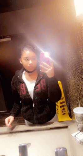A Woman Taking A Selfie In Front Of A Mirror With A Yellow Caution Sign In The Background GIF