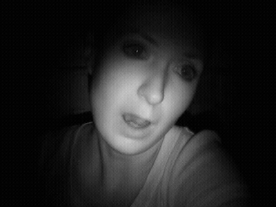 A Woman Taking A Selfie In The Dark With Her Eyes Closed GIF