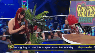 A Woman Talking Into A Microphone With A Sign That Says Grayson Waller Effect GIF