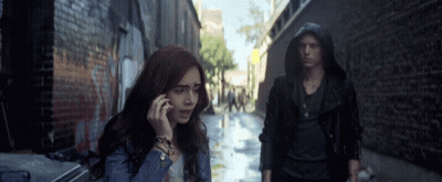 A Woman Talking On A Cell Phone While A Man Stands Behind Her GIF