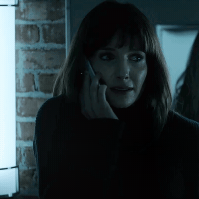 A Woman Talking On A Cell Phone With A Brick Wall In The Background GIF