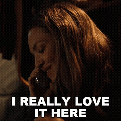 A Woman Talking On A Cell Phone With The Words I Really Love It Here Above Her GIF