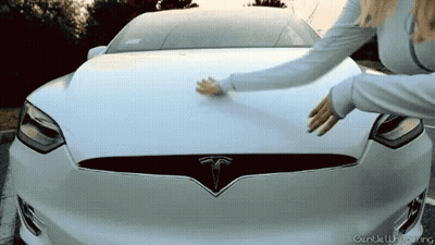 A Woman Touches The Hood Of A White Tesla GIF