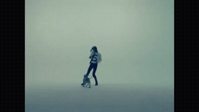A Woman Walking A Dog With The Letter S On Her Shirt GIF