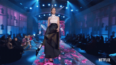 A Woman Walking Down A Runway With A Netflix Logo In The Background GIF