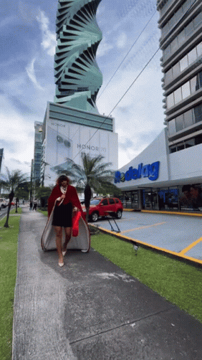A Woman Walking Down A Sidewalk In Front Of A Store That Says Redelag GIF