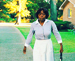 A Woman Walking Down A Sidewalk With A Tennis Racquet GIF