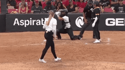 A Woman Walking On A Baseball Field In Front Of A Sign That Says Aspirational GIF